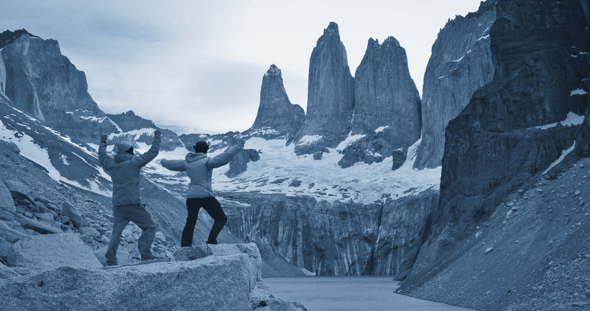Two hikers with arms raised below the towers of Torres del Paine