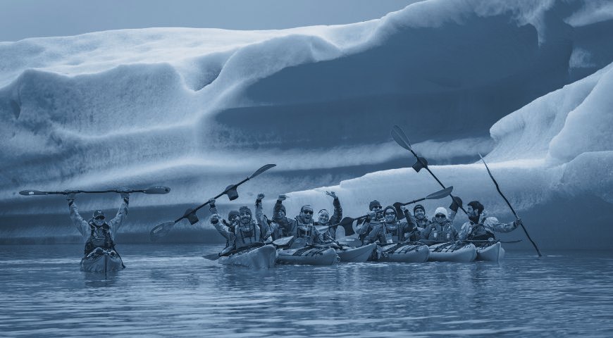 Kayakers paddling among icebergs